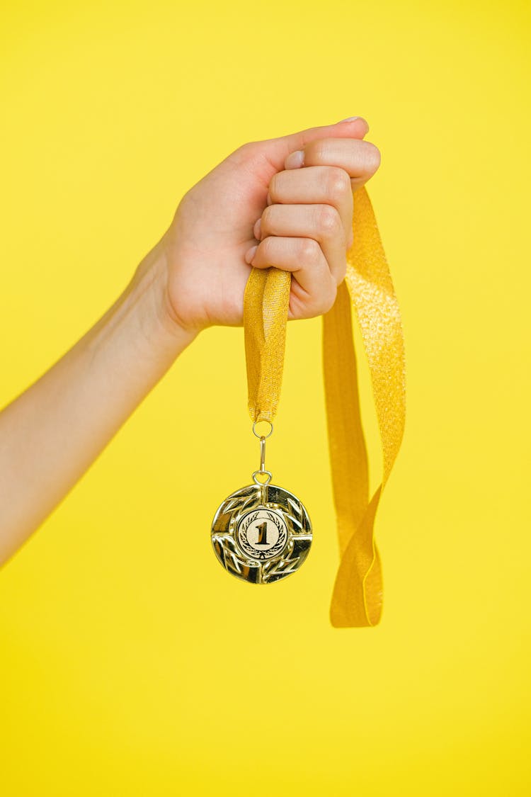 Person Holding A Gold Medal