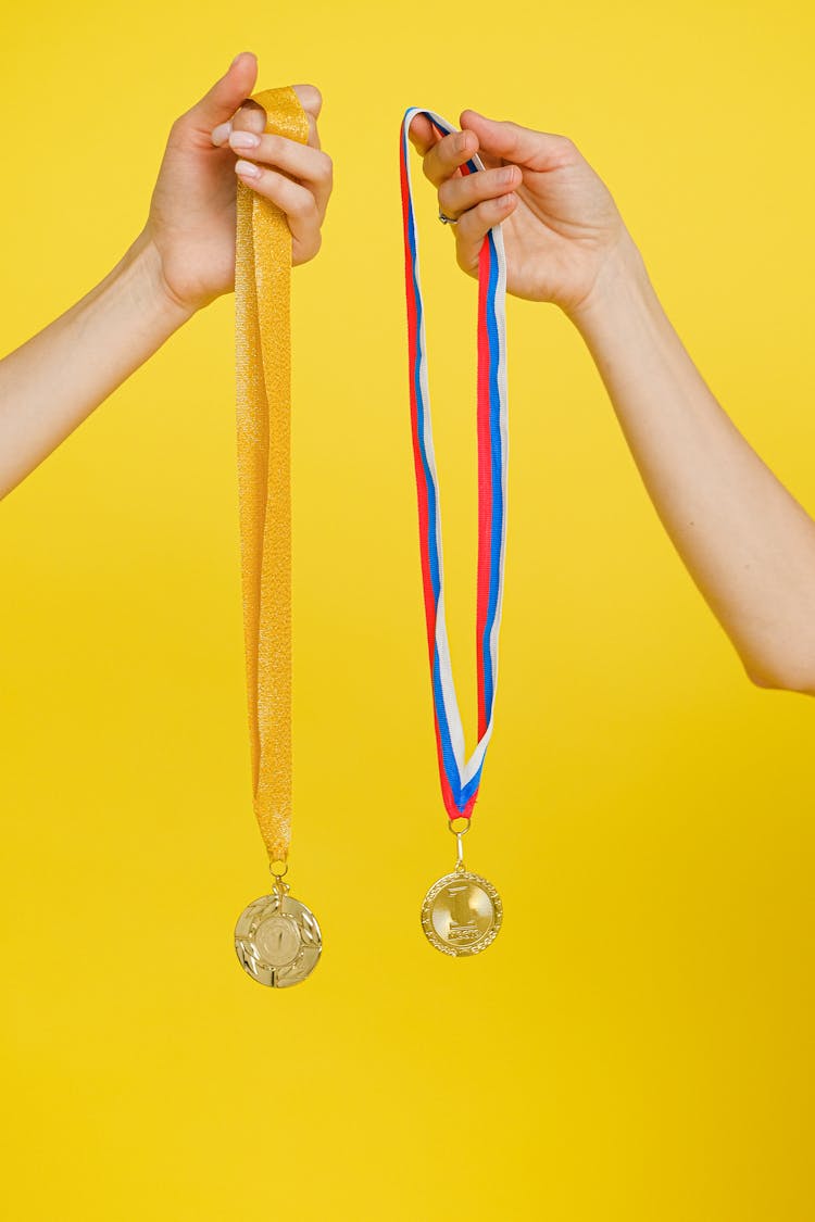 Close-Up Shot Of A Person Holding Gold Medals