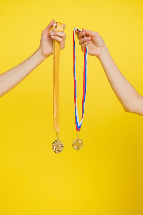 Close-Up Shot of a Person Holding Gold Medals