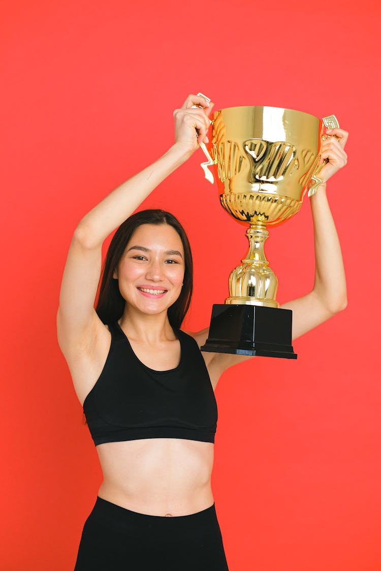 Woman In A Black Sports Bra Holding A Trophy