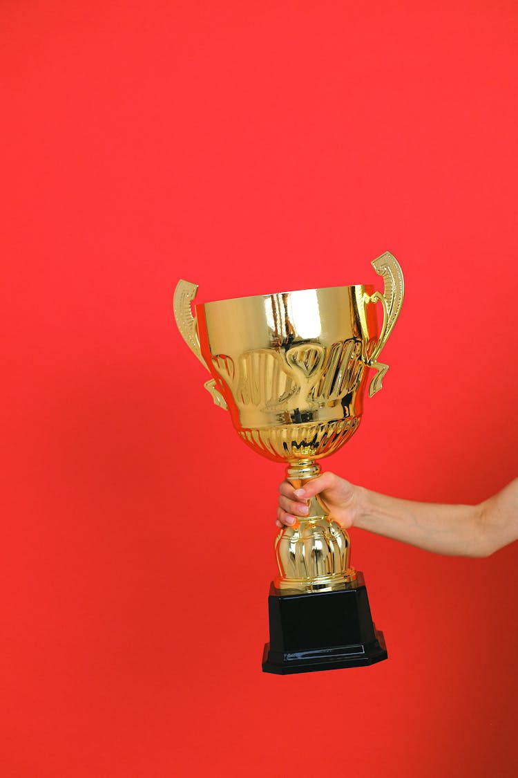 Close-Up Shot Of A Person Holding A Gold Trophy