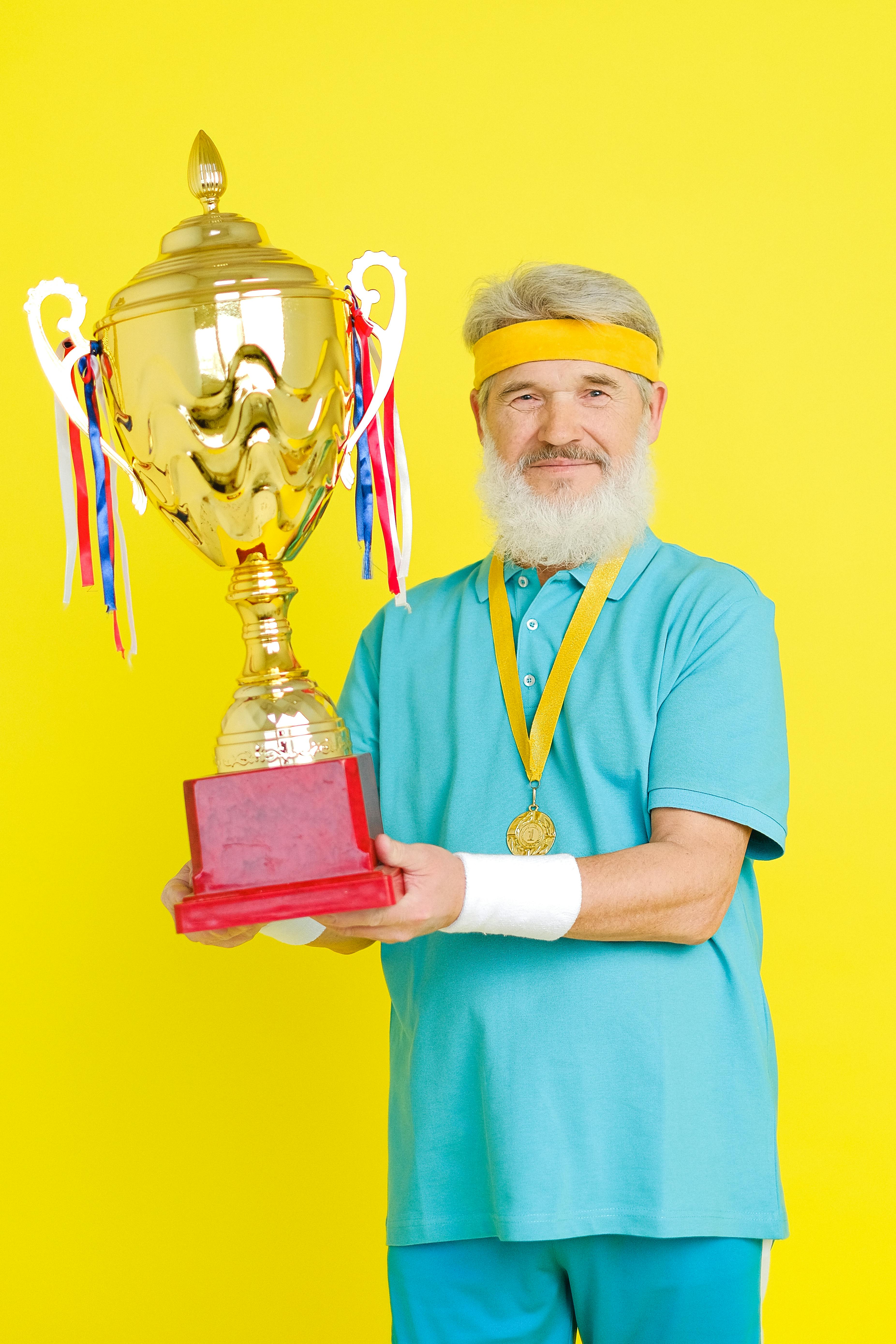 an elderly man winning a gold trophy