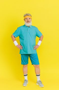 Senior man in vibrant activewear standing confidently against a vivid yellow backdrop.