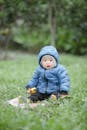 A Cute Child in Blue Jacket Sitting on the Grass