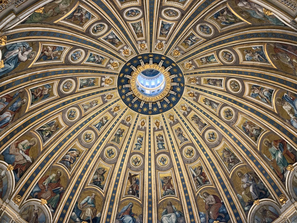 From below amazing dome ceiling with ornamental fresco paintings and stucco elements in St Peters Basilica in Rome