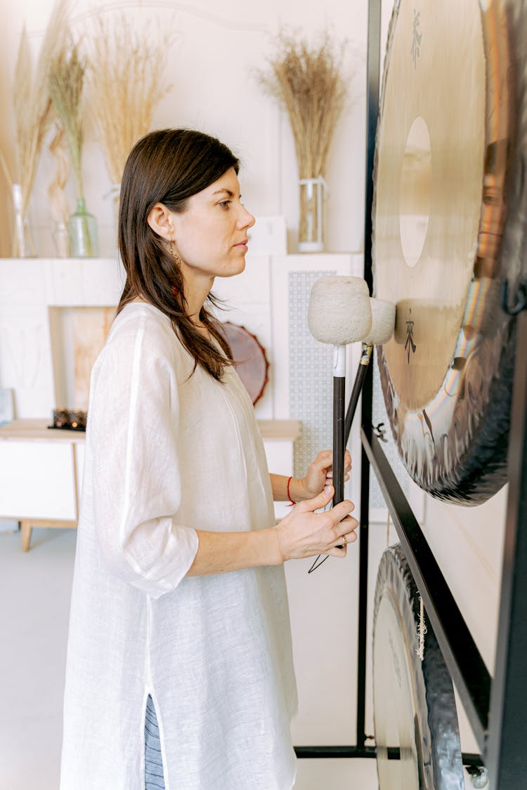 A Woman Playing A Gong