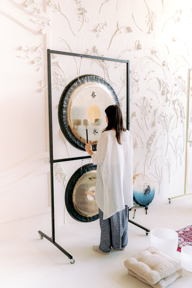 A Woman Playing A Gong