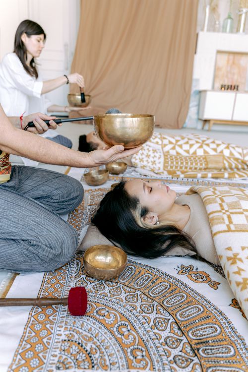 Free Woman experiencing relaxation with Tibetan singing bowl therapy indoors. Stock Photo