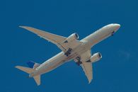 From below of aircraft for transporting passengers with landing gear prepared for landing on blue sky