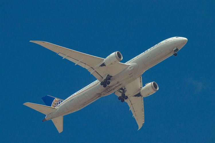 Airplane With Landing Gear Flying Over Blue Sky