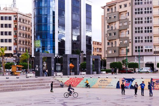 Children playing in a lively public square in Oujda, Morocco with modern buildings.