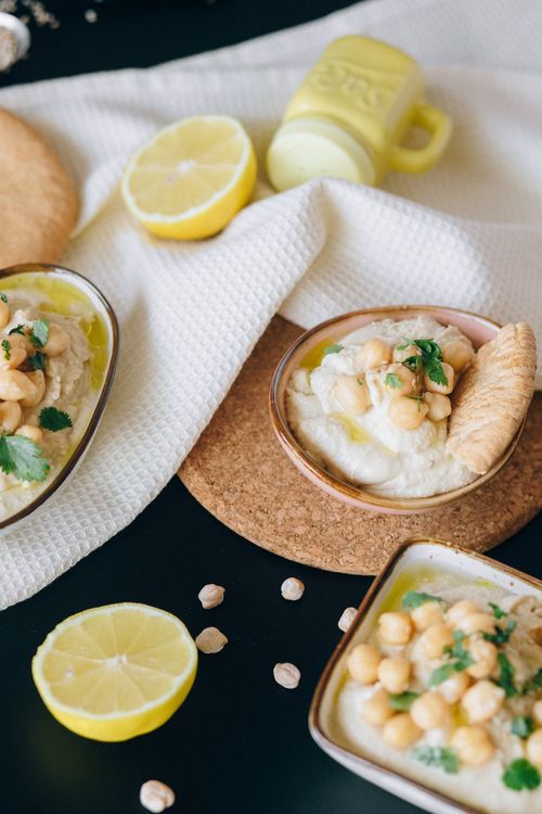 Free A close-up of creamy hummus topped with chickpeas, lemon slices, and fresh herbs. Stock Photo