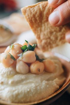 Delicious close-up of hummus topped with chickpeas and herbs, alongside bread for dipping.