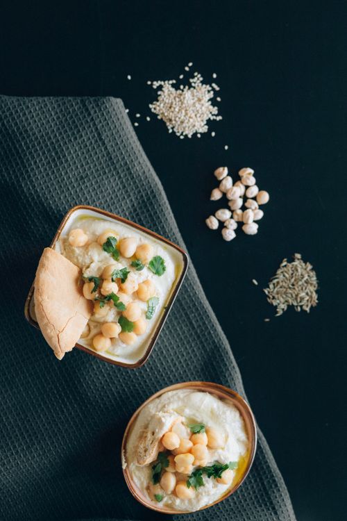 Free Fresh hummus with chickpeas and herbs served from above, paired with pita on a dark background. Stock Photo