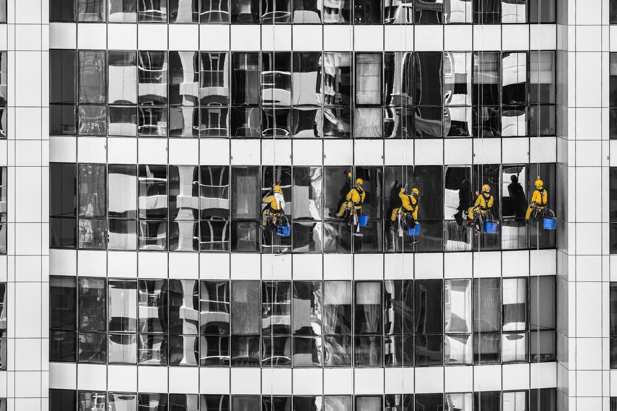 Team of window cleaners working on a high-rise glass building