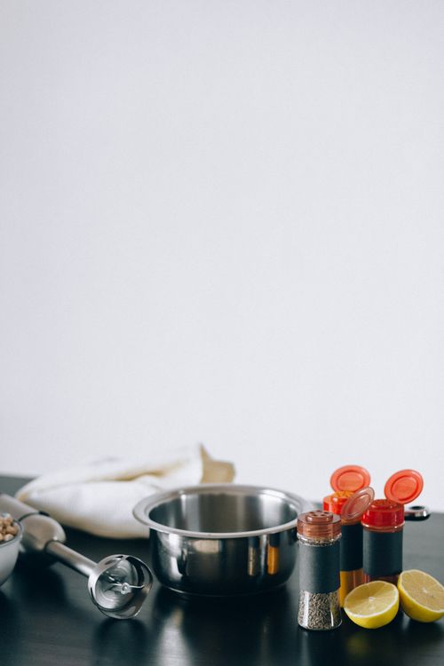 Free A minimalist kitchen scene with spices, a mixing bowl, and sliced lemons on a dark counter. Stock Photo