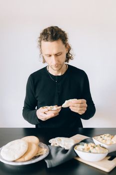 A man enjoying a Mediterranean meal with pita bread indoors.