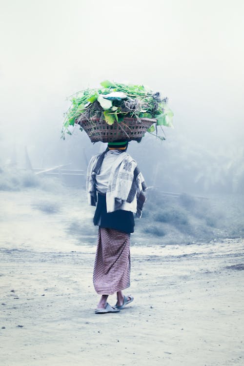 Woman Carrying Basket with Leaves on Head