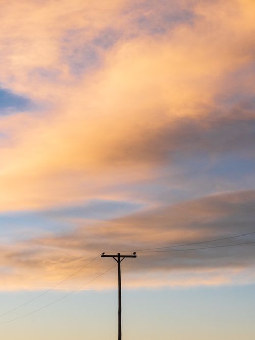 Free Silhouette of a utility pole against a vibrant sunset sky in Estancia, New Mexico. Stock Photo