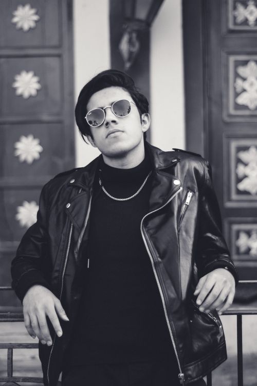 Free Monochrome portrait of a stylish man wearing a leather jacket and sunglasses posing confidently. Stock Photo