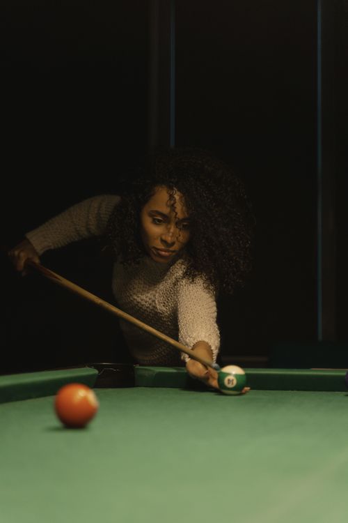 Free African American woman concentrates while playing billiards indoors. Stock Photo