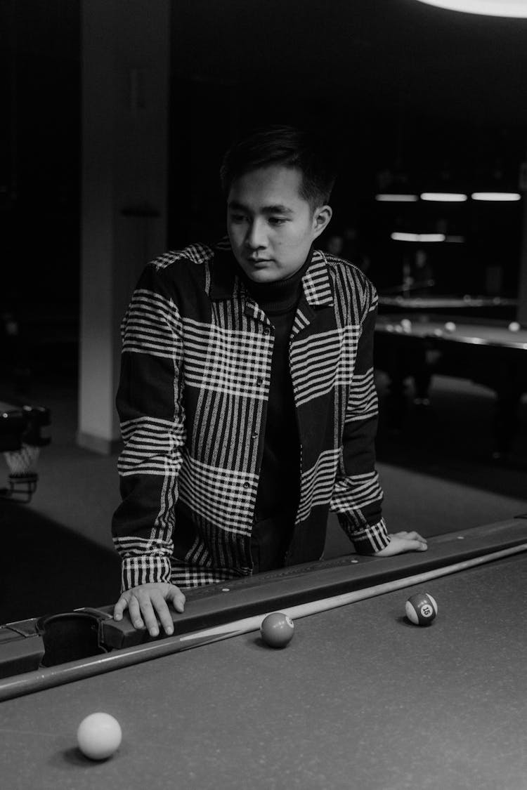 Black And White Photo Of A Man Standing Near A Pool Table