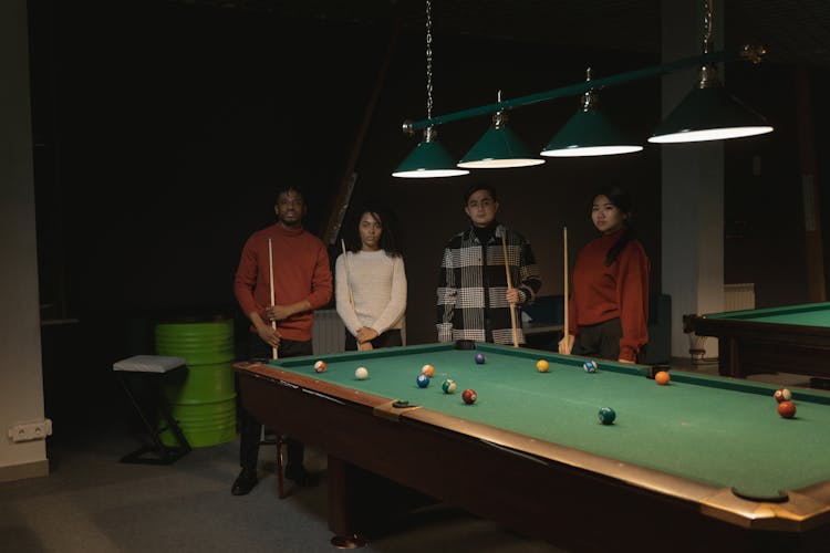 Photo Of A Group Of Friends Standing Near A Pool Table