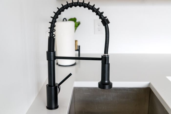 Matte black pull-down kitchen faucet over a deep steel sink