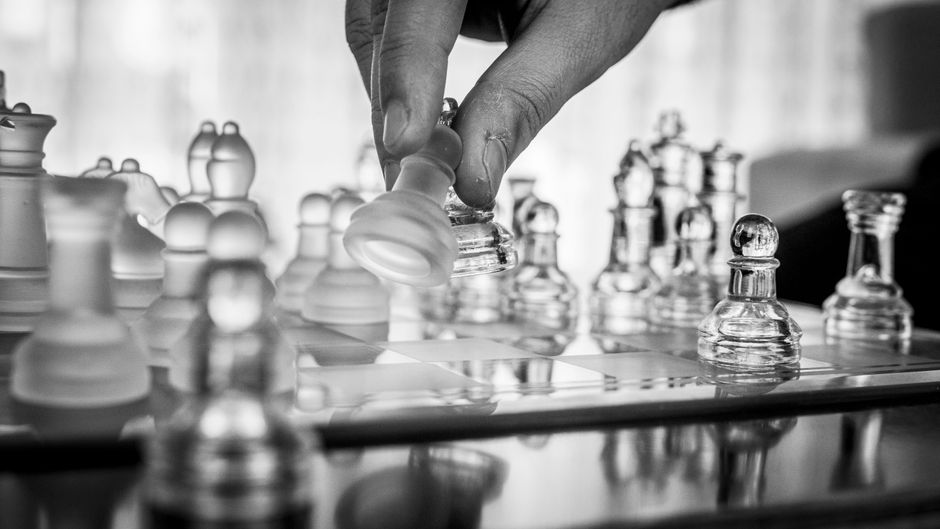A hand moves a glass chess piece, an image of strategy and defensibility