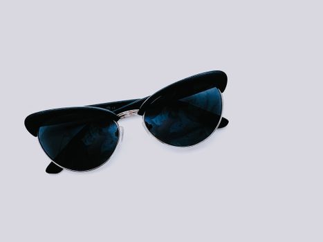 From above of trendy sunglasses with dark lenses and creative design placed on clear white background in modern light studio