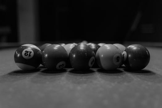 Artistic black and white close-up of billiard balls on a pool table, emphasizing texture and contrast.