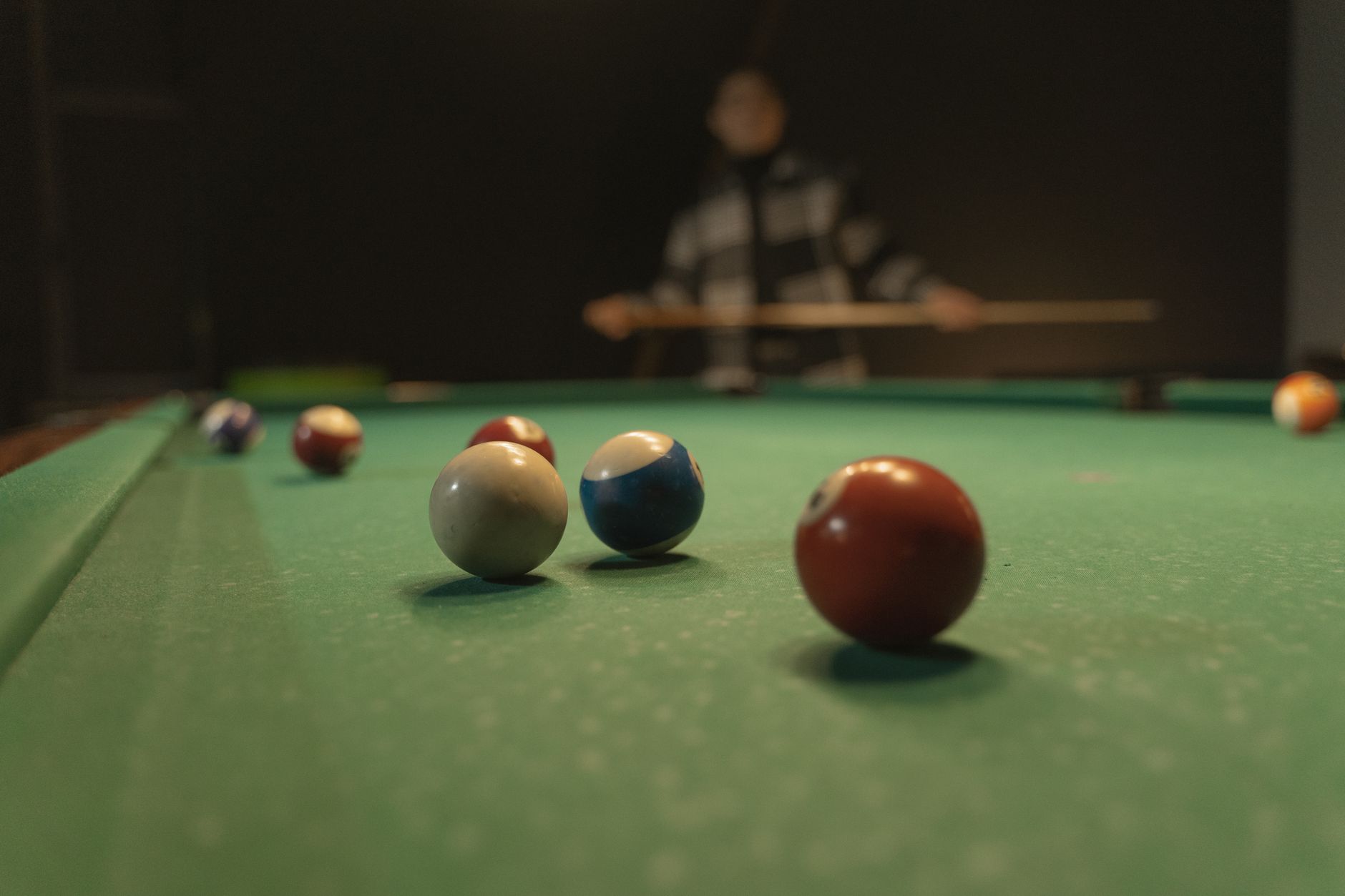 A vibrant shot of a billiards table with focused cue balls, capturing a player in the background.