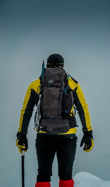 Fotomural Vista trasera de un mochilero con ropa de invierno caminando por el paisaje nevado de Eslovenia.