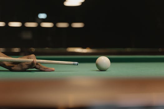 Close-up of a hand preparing to strike a cue ball in billiards with precise focus.