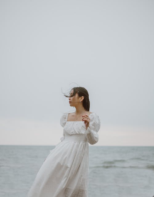 Donna In Abito Bianco Manica Lunga In Piedi Sulla Spiaggia