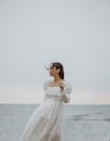 一名女子凝视大海，穿着白色连衣裙，优雅地站在宁静的海景中