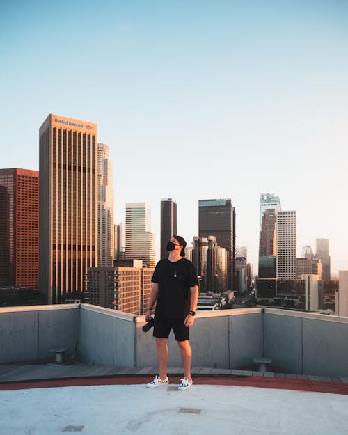 Man in Black Hoodie and Black Shorts Standing on Top of Building