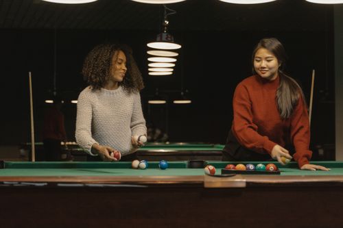 Free Two women playing billiards indoors, enjoying a casual game and socializing. Stock Photo