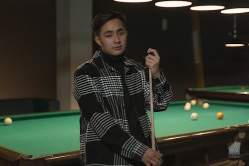 Free Man in a Black and White Shirt Holding a Cue Stick Stock Photo
