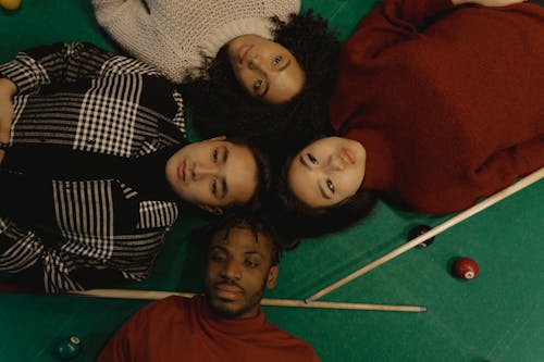 Overhead Shot of a Group of Friends Lying Down on Top of a Billiard Table