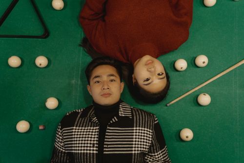 Free A man and a woman lie on a billiard table surrounded by billiard balls and a cue stick. Stock Photo