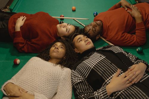 Free Four friends lying together on a pool table showcasing diversity and friendship. Stock Photo
