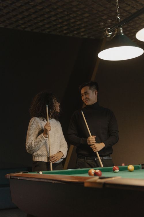 Free A man and woman enjoy playing billiards together in a cozy indoor setting. Stock Photo