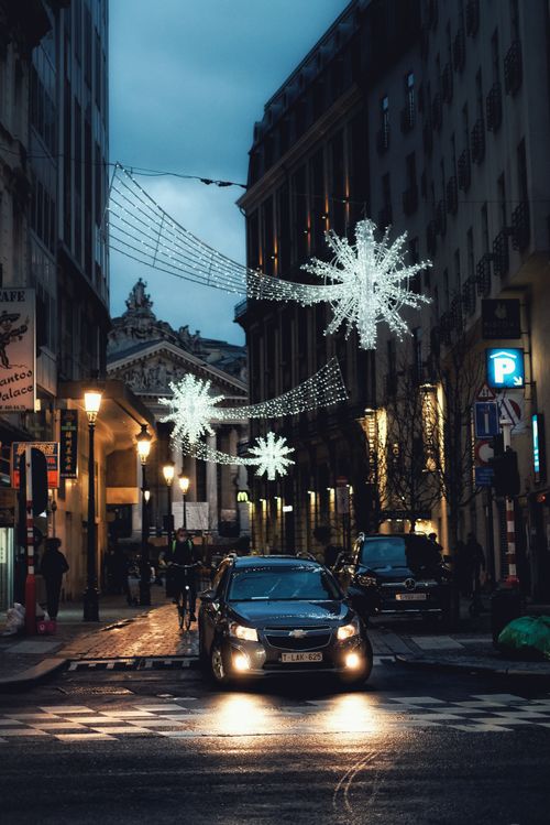 Free A festive night scene in Brussels with illuminated Christmas decorations and bustling urban life. Stock Photo