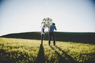 两个成年人在阳光明媚的田野里，用相机捕捉大自然，头顶是明亮的夏日天空