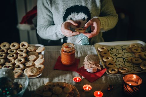 Free Freshly baked Christmas cookies being prepared with jam in a cozy setting. Stock Photo