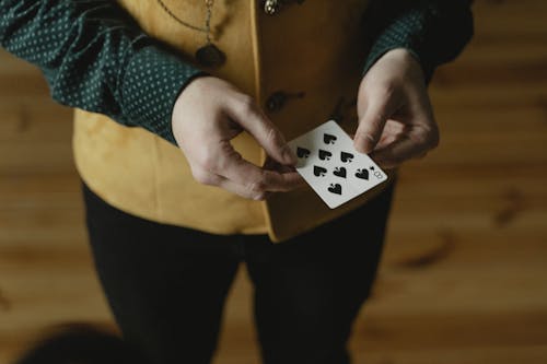 Photo of a Person's Hands Holding a Playing Card