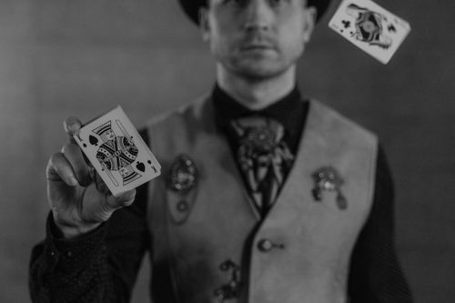 Free Close-up black and white image of a man performing card tricks with precision and flair. Stock Photo