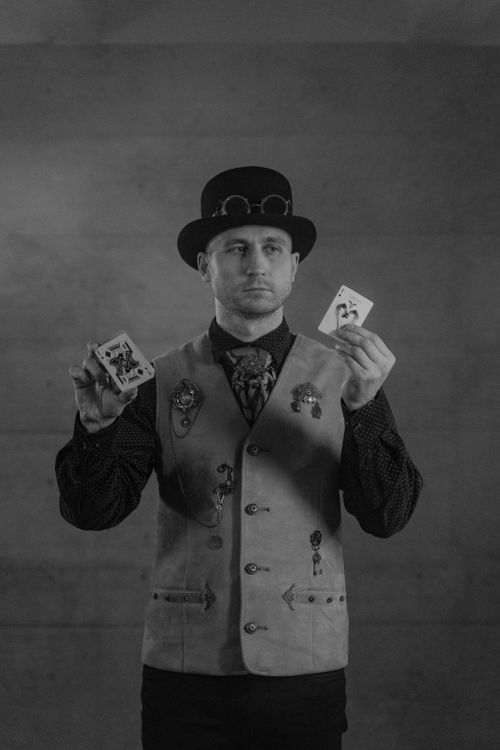 Free A magician performs a card trick in steampunk attire, creating a mysterious atmosphere. Stock Photo
