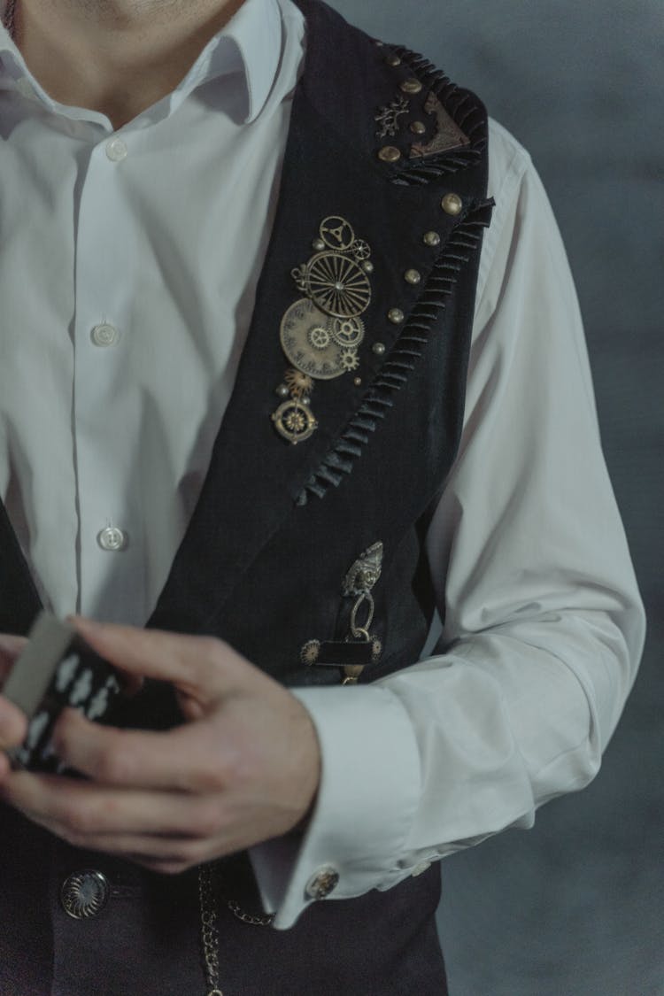 A Man In A Vest With Trinkets Holding A Deck Of Playing Cards